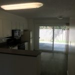 College Street Apartments kitchen with white cupboards and dark gray counters looking through slider to back patio area